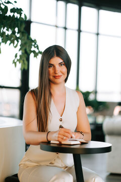 Woman writing in a notebook at a table in a modern office