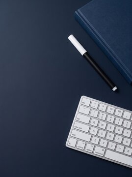 Stylish workspace setup featuring a keyboard pen and notebook against a dark backdrop