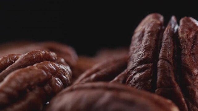 Extreme macro shot of fresh premium pecan nuts with selective focus, rotating slowly on dark background with artistic lighting. Perfect for healthy eating, gourmet food, culinary, and dietary content.