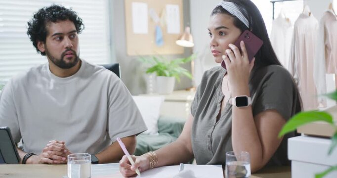 In studio African American team working, woman taking client call on phone while jotting notes