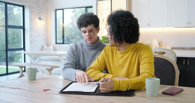 African American man in mustard sweater male teen gray reviewing folder kitchen table