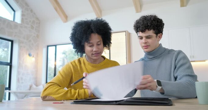African American male partners, one teen, leaning in signing papers in kitchen for red key fob