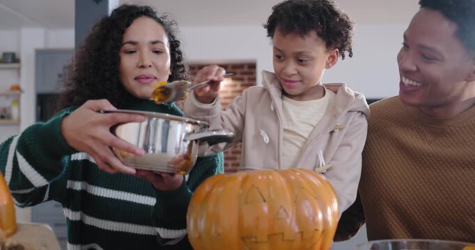 African American family prepping pumpkin at home drawn face urging child scooping seeds into pot