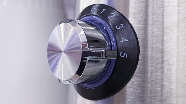 Man Turning Control Knob on Home Appliance. Close-up of fingers adjusting a numbered setting. Concept of household technology, power control, settings and everyday domestic use.