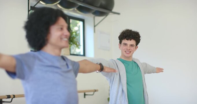 During fitness class, Diverse adult male peers holding T-pose, moving forward near barre, smiling