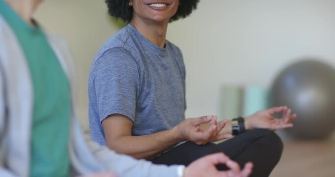 Adult African American male smiling speaking settling into Gyan mudra for calm breath on yoga mat