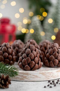 Christmas chocolate brownie pine cones with chocolate flakes and powdered sugar on a wooden board on a gay background. Christmas and New Year delicious dessert. Copy space.