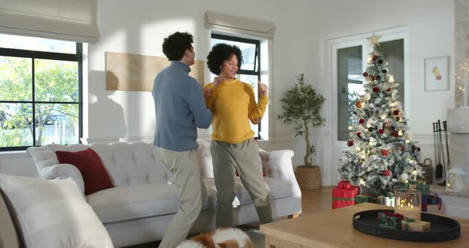 Two African American male friends dancing, holiday lights sparking mirroring hand moves near couch