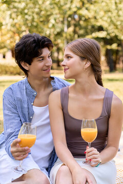 A happy couple shares a romantic picnic in a lush green park under the sun