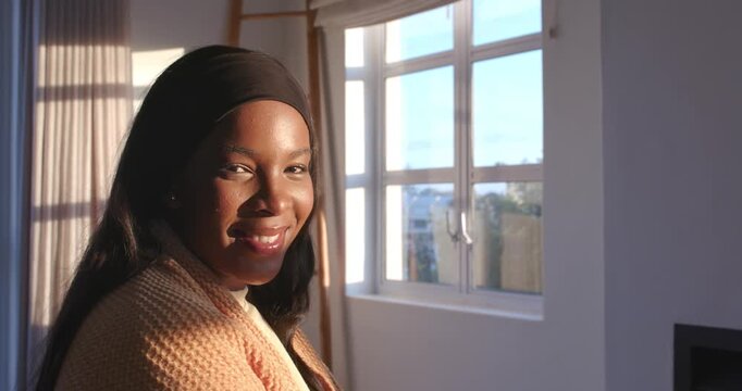 African American adult woman turning toward camera and laughing as sunlight shifts through window