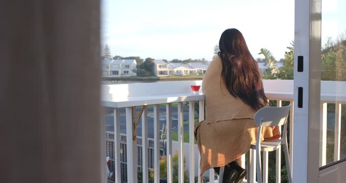 African-American woman sitting balcony rail sipping red cup, turning head hearing noise, copy space