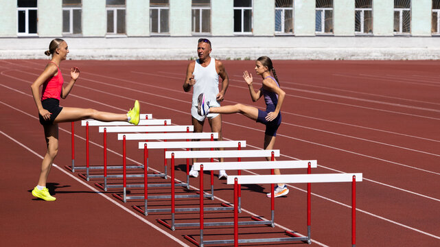 Female high jump athletes move through hurdle line during track practice. Concept of dynamic warmup, agility, coordination, sports teamwork and competition preparation.