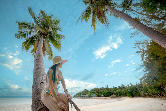 Woman tourist stay enjoy the nature of summer on the tropical island under shadow of the coconut palm trees at the edge of the sea beach