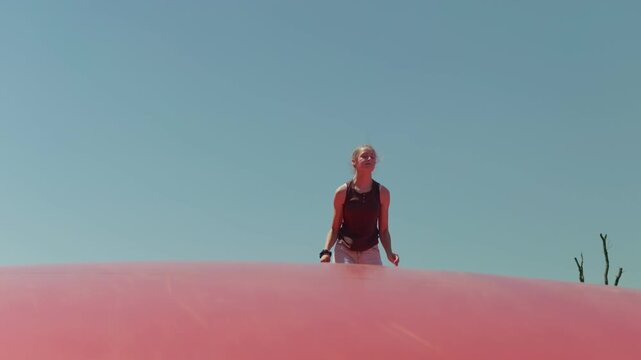 A girl does the splits while jumping the sky in the background slow motion