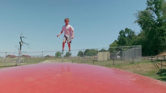A boy is doing somersaults on a trampoline zoom in