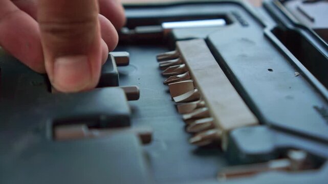 Hand placing screwdriver bit into toolbox case, close up shot, workshop tool organization, hardware equipment footage scene.