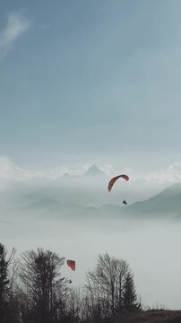 Paragliders flying over Gaisberg mountain with Watzmann and Untersberg in the background, Austria