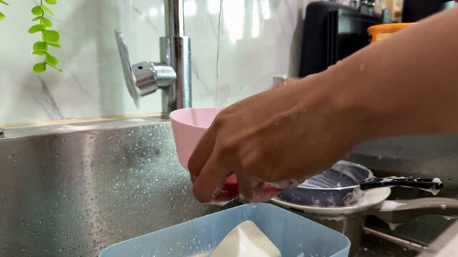 fingers scrubbing kitchenware under faucet, dishwashing routine, cleaning and household concept.