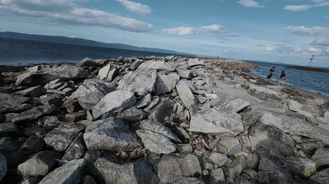 Pan along a granite rock breakwater at the edge of the Trondheimsfjord
