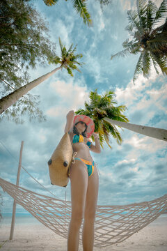 Woman tourist stay enjoy the nature of summer on the tropical island under shadow of the coconut palm trees at the edge of the sea beach