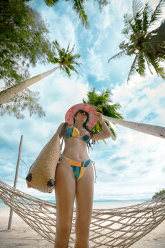 Woman tourist stay enjoy the nature of summer on the tropical island under shadow of the coconut palm trees at the edge of the sea beach