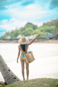 Woman tourist stay enjoy the nature of summer on the tropical island under shadow of the coconut palm trees at the edge of the sea beach