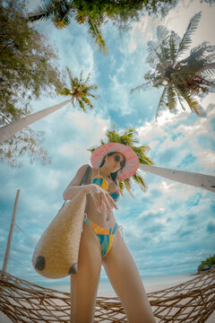 Woman tourist stay enjoy the nature of summer on the tropical island under shadow of the coconut palm trees at the edge of the sea beach