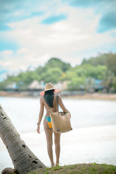 Woman tourist stay enjoy the nature of summer on the tropical island under shadow of the coconut palm trees at the edge of the sea beach
