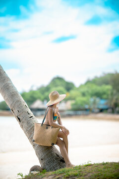 Woman tourist stay enjoy the nature of summer on the tropical island under shadow of the coconut palm trees at the edge of the sea beach