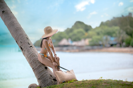 Woman tourist stay enjoy the nature of summer on the tropical island under shadow of the coconut palm trees at the edge of the sea beach