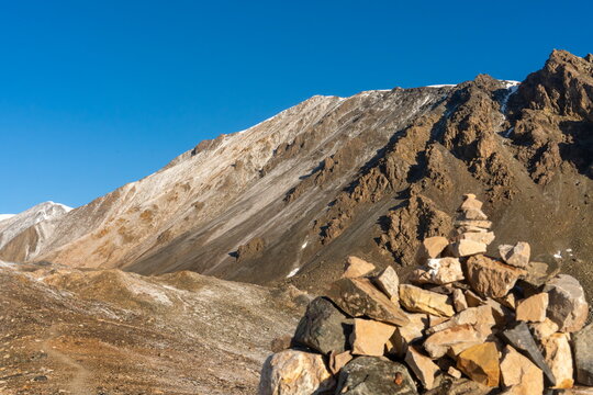 Cairn overlooks Yukhin Peak near Lenin Peak Camp 1 under clear blue sky, August