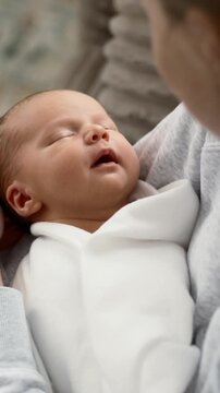 Mom Rocking Newborn Baby In Arms While Sitting On The Couch In Vertical Video
