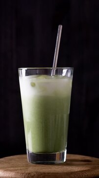 Woman Bartender Pours Green Matcha Into A Glass With Milk And Ice Close-Up While Making Green Matcha Latte. Vertical Video
