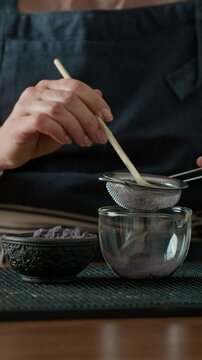 Woman Sieves Blue Matcha Tea Into A Bowl Through A Strainer Close-Up. Vertical Video