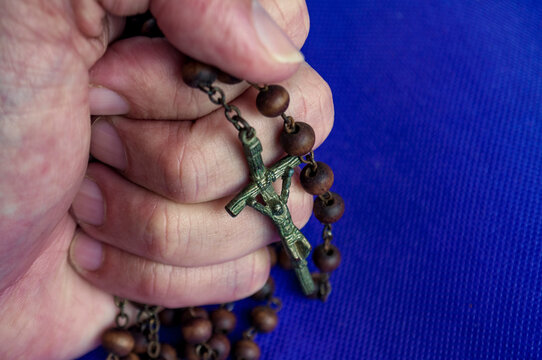 Hand holding Holy Rosary representing Christianity prayer and faith.
