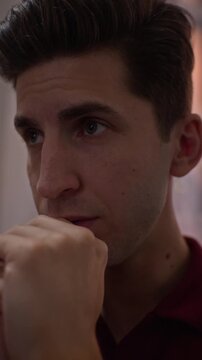 Vertical shot of stressed young adult Caucasian man watching sports game at home, reacting with disappointment and covering face. Footage ideal for sports betting campaigns and fandom promotions