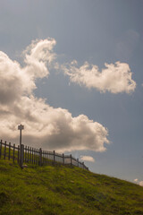 Obraz premium Mountain Meadow And Fence Beneath Dramatic Cloudy Sky