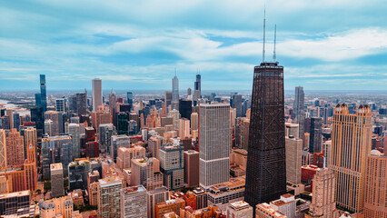 Naklejka premium John Hancock Center and Chicago skyscrapers view. Aerial photograph of dark tall tower with antennas standing among modern office buildings under blue sky.