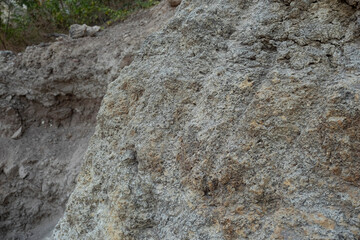 Stone mountain texture. A close up view of a steep stone quarry face showing intricate rocky layers and rough textures of excavated limestone under bright daylight. © Luqman Aditiamala