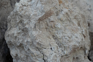 Stone mountain texture. A close up view of a steep stone quarry face showing intricate rocky layers and rough textures of excavated limestone under bright daylight. © Luqman Aditiamala