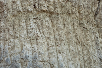 Stone mountain texture. A close up view of a steep stone quarry face showing intricate rocky layers and rough textures of excavated limestone under bright daylight. © Luqman Aditiamala