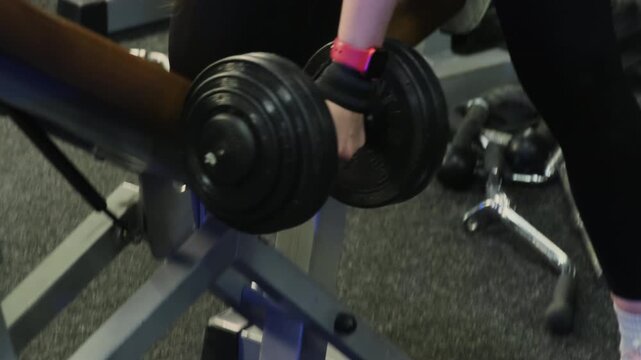 Sportswoman performs powerful arm curls with heavy dumbbell. Athlete maintains excellent balance and concentration during exercise