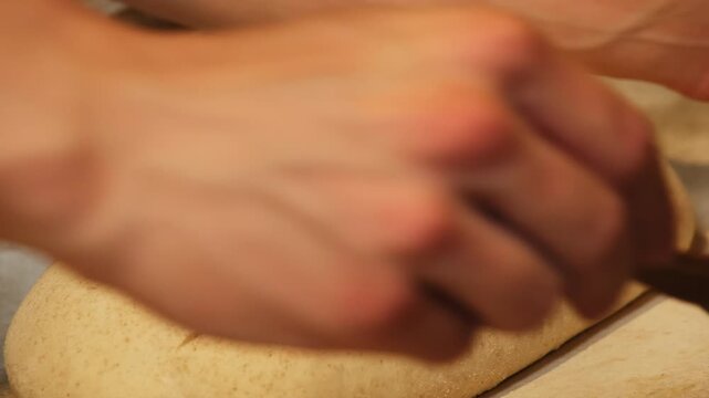 Baker hand with razor scores unbaked bread loaf on tray closeup. Chef slashes simple pattern on wheat bun in bakery workshop. Organic food