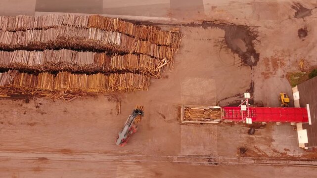 Top-down aerial of a log loader lifting logs onto a conveyor at a pulp and paper mill, Gratkorn, Styria, Austria