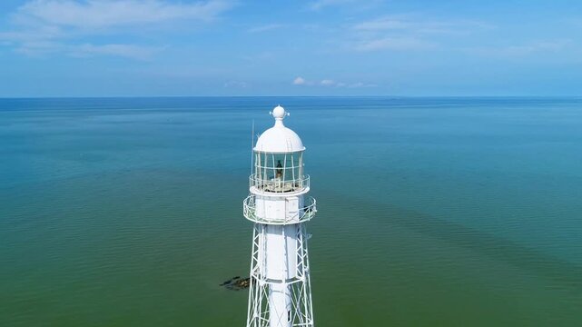 White lighthouse overlooking calm ocean under clear blue sky