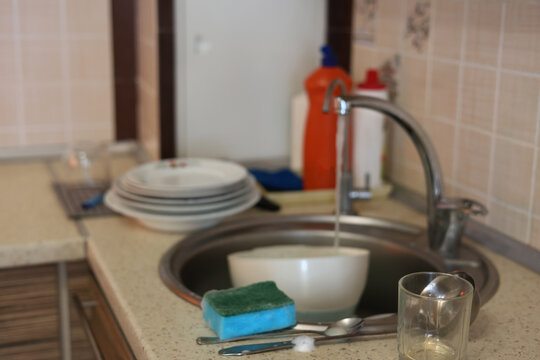 Kitchen sink with running water and a sponge on the counter, household chores and domestic routine stock photography