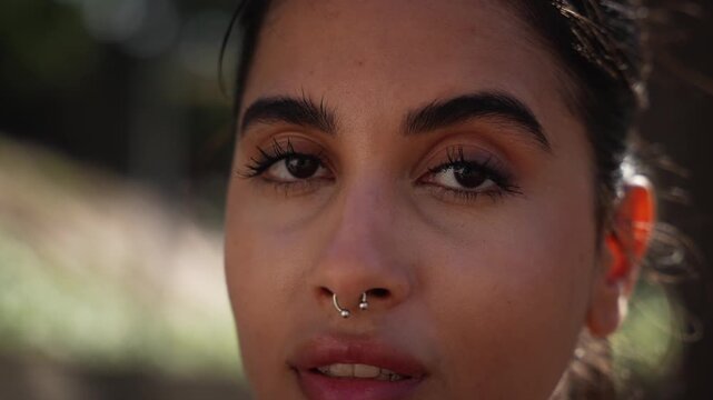 Close up portrait of a beautiful young woman looking at camera carefree outdoors.