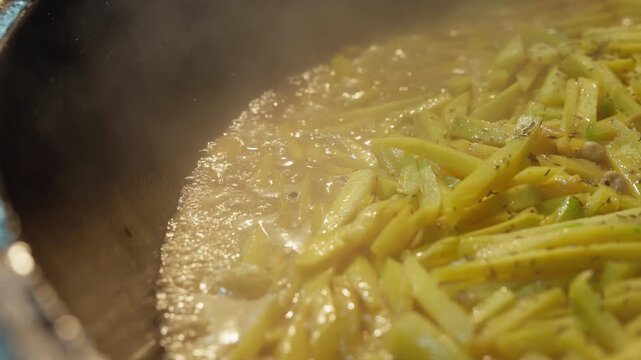 Close-up of bubbling zirvak, the rich aromatic base for traditional Uzbek plov, cooking in a large kazan with sliced carrots and spices. Authentic Central Asian culinary 