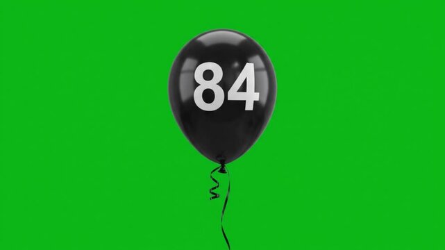 Black balloon with number 84 floating on green screen
