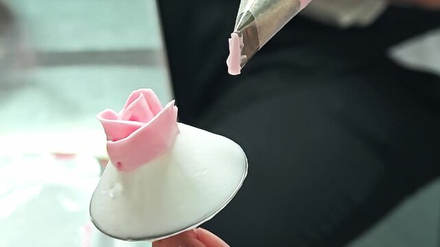 Alternative view of piping a pink buttercream rose bud for cake decoration.